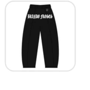 Svarta mjukisbyxor med vit text - Svarta mjukisbyxor med bred passform och vit tryckt text över höfterna. Byxorna har resår i midjan och är perfekta för en avslappnad streetwear-look. Passar bra till sneakers och hoodie.