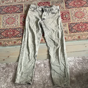 Grå acid wash jeans från Jack & Jones - Säljer ett par gråa acid wash jeans från Jack & Jones. Byxorna har klassisk femficksdesign, raka ben och normal passform. Snyggt slitna detaljer och svart läderpatch med logga bak i midjan.