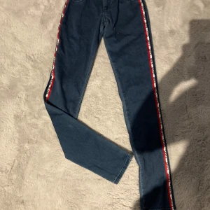 Levi's 710 Super Skinny jeans med logoband - Mörkblå Levi's 710 Super Skinny jeans med vita och röda logoband längs sidorna. Klassisk femficksmodell med smal passform och hög midja. Snygga detaljer som ger en sportig vibe.