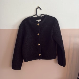 Svart teddyjacka med guldknappar från Gina Tricot - Svart kofta från Gina tricot med knappar! Koftan är lite tjockare och kan även andvändas som en jacka! Det är barnstorlek men passar även nog de som brukar ha xs! Skriv till mig innan ni trycker på köp nu💘