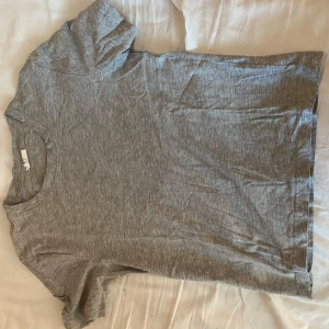 Grå t-shirt från Gina Tricot - En basic grå t-shirt från Gina Tricot i mjuk bomull. T-shirten har rund halsringning och korta ärmar, perfekt för en enkel och avslappnad stil.