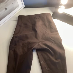 Bruna ridleggings från HMs rid märke  - Mörkbruna ridleggings från Aim'n med hög midja och diskreta ventilationsdetaljer på benen. Stretchigt material som ger bra rörelsefrihet och komfort. Perfekta för ridning och träning.