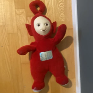 Teletubbies - Po - Mjukisdocka föreställande Po från Teletubbies. Perfekt för dig som älskar nostalgi och vill ha en ikonisk karaktär från barndomen i samlingen. Passar både som dekoration och kramkompis.