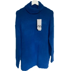 Blå polotröja från Zara - En stilren blå polotröja från Zara med lång ärm och hög krage. Perfekt för lager-på-lager och enkel att matcha med jeans eller kjol. Mjuk och skön känsla. 