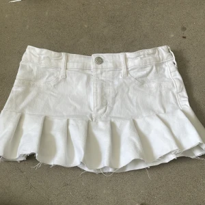 Lågmidjad vit jeanskjol  - Jag säljer en vit Lågmidjad jeanskjol. Den är i storlek 146 och midijemåttet är 65 cm. Den har också justerbar midja.