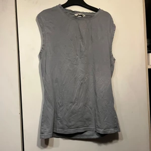 Blå ärmlös topp från H&M - En enkel och stilren blå ärmlös topp från H&M. Toppen har rund halsringning och är tillverkad i mjuk bomull, perfekt för en avslappnad look. STORLEKEN ÄR I BARN STORLEK! 