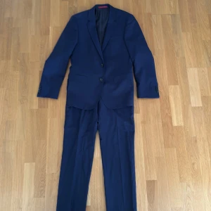 HUGO BOSS - Marinblå kostym full set (kavaj + kostymbyxor)  - Säljer min studentkostym som är i toppenskick som ny och bara använts en gång. Det är ett komplett kostymset med marinblå kavaj och kostymbyxor från HUGO BOSS. Perfekt för bal, kalas, student eller något annat festligt tillfälle. Storlek 46 på både kavajen och byxorna. Tveka inte om ni har några frågor. 