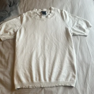 Vit kortärmad tröja från Lindex - Säljer en stilren vit kortärmad tröja från Lindex. Tröjan har rund halsringning och är tillverkad i ett mjukt material som passar perfekt till sommaren. Enkel och clean design som funkar till många olika outfits.