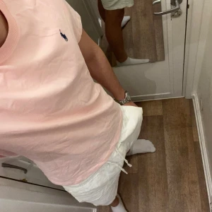 Polo Ralph Lauren (Rosa T-shirt) - Säljer en stilren rosa t-shirt från Polo Ralph Lauren med det klassiska broderade logotypen i blått på bröstet. T-shirten är oanvänd och redo för en ny ägare! Perfekt för en avslappnad look. Den är storlek L! Men passar M också.