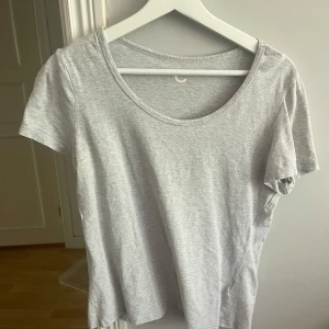 Ljusgrå basic t-shirt - En enkel ljusgrå t-shirt med rund halsringning och korta ärmar. Perfekt för en clean och avslappnad stil. T-shirten har en normal passform och är tillverkad i mjukt bomullsmaterial.