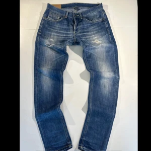 🔥Dondup George 🔥 - Säljer ett par blå jeansbyxor från Dondup med slitningar och ljusa partier framtill och med passform slimfit. Byxorna har knäppning med knappar och klassisk femficksdesign.        Passar dig som vill höja din outfit ett steg!!  🍾🍾