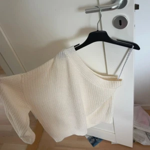 Vit stickad offshoulder-tröja från Noisy May - Säljer en vit stickad offshoulder-tröja från Noisy May. Tröjan har en ribbad struktur och är perfekt för dig som gillar en trendig och avslappnad stil. Passar snyggt till både jeans och kjol.