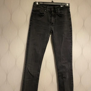 Svarta jeans från Never Denim - Säljer ett par svarta jeans från Never Denim med klassisk femficksdesign och raka ben. Jeansen har hög midja och stängs med knapp och dragkedja. Perfekta till många olika outfits.