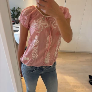 Rosa blus med broderade detaljer - Säljer en söt rosa blus med vita broderade mönster framtill och vid axlarna. Perfekt för vår och sommar! från odd Molly.   Deras storlekar är i siffror, denna i 0, skulle säga en S! Super fint skick ⭐️🩷