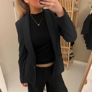 Svart/grå  kostym med kavaj och byxor - Säljer en svart kostym med klassisk kavaj och matchande byxor. Kavajen har enkel knäppning och en rak passform. Perfekt för dig som vill ha en stilren och tidlös look.☺️