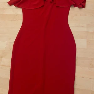 Röd klänning med volang och knappar från NA-KD - Säljer en snygg röd klänning från NA-KD med off shoulder hål och dekorativ knapp vid stängningen. Klänningen har en figurnära passform och är perfekt för dig som vill sticka ut. Materialet känns mjukt och följsamt. 💋🌹❤️❤️❤️❤️❤️❤️❤️❤️❤️❤️❤️❤️❤️❤️❤️❤️‍🔥