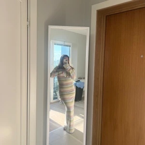 Pastellrandig stickad långklänning med slits - Säljer en mysig stickad långklänning från Lojsan Wallins kollektion med NAKD, med pastellfärgade ränder i ljusblått, gult, rosa och vitt. Klänningen har lång ärm, rund hals och en hög slits på ena sidan. Perfekt för dig som gillar färg och vill ha något bekvämt men ändå snyggt.