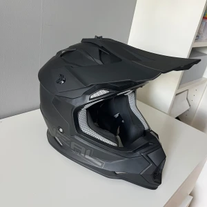 Svart motocrosshjälm från O'Neal - Säljer en mattsvart motocrosshjälm från O'Neal med sportig design och vit ventilerad inredning. Hjälmen har skärm framtill och robust konstruktion, perfekt för dig som gillar fart och äventyr.