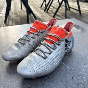 Adidas X 16.1 fotbollsskor - Säljer mina gamla fotbollsskor då de inte passar. Adidas X 16.1 i färgen Metallic/Solar red. Enligt Unisport ska de passa spel på både konstgräs och vanligt gräs (FG+AG dobbar). Storlek 41 1/3, ca 26cm, UK 7.5. Skriv vid frågor/funderingar!
