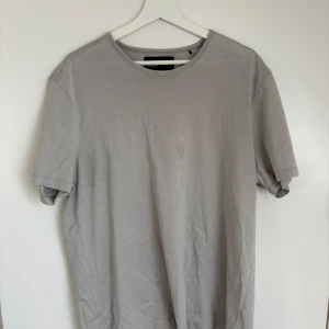 Ljusgrå t-shirt från Limitato x Brigitte Bardot - Säljer en ljusgrå t-shirt från Limitato med ett svartvitt fotomotiv på ryggen. T-shirten har rund hals och korta ärmar. Perfekt för dig som gillar stilrena plagg med en twist. Den har en lite fläck men inget som syns direkt, går att få bort.