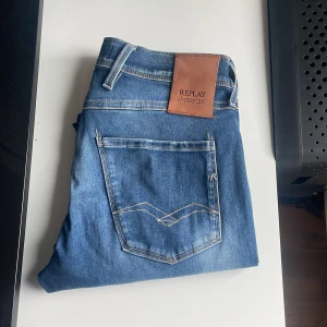 Replay Anbass jeans blå - Säljer ett par Replay Hyperflex Anbass jeans i blå tvätt med slitningar och distressed detaljer. STRL W29/L32. Jeans är bra kvalitet tecken på användning och tvättning men inga defekter eller annat. Hör av dig vid mer frågor.