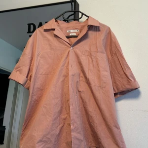 Rosa kortärmad skjorta från Zara - Säljer en stilren rosa skjorta från Zara med relaxed fit. Skjortan har korta ärmar, klassisk krage, bröstficka och knäppning framtill. Helt nytt