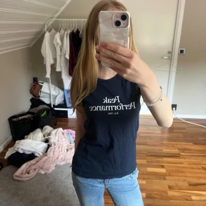 Mörkblå Peak Performance t-shirt XS - Marinblå t-shirt från Peak Performance med vit logga och text på bröstet. Rund halsringning och korta ärmar. Storlek XS, knappt använd.