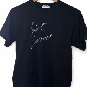 Saint Laurent T-shirt - En snygg T-shirt från Saint Laurent i storlek S! Vet ej om den är äkta, därav det låga priset för en sådan fin tröja. Mycket fint skick. 