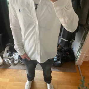 Vit långärmad skjorta Polo Ralph Lauren - Kvitto finns! Vit långärmad skjorta från Polo Ralph Lauren med klassisk krage och knappar framtill. Skjortan har broderad blå logga på bröstet och är tillverkad i mjuk bomull. Perfekt för en clean och stilren look. 