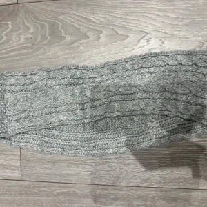 Ljusgrå stickad halsduk med flätmönster för barn  - Mysig ljusgrå halsduk med snyggt flätstickat mönster. Perfekt för kalla dagar och enkel att matcha med olika outfits. Tjock och varm, passar dig som gillar klassisk stil.