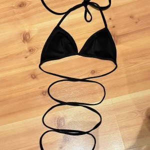 Svart bikini med snörning - Snygg svart bikini med trekants-bh och långa snören som kan lindas runt midjan för en trendig look. Perfekt för stranden eller poolen. Enkel och stilren design som passar dig som gillar minimalistiskt.