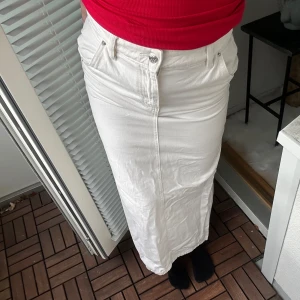 Jeanskjol - Lång vit jeanskjol med slits bak från gina i storlek 32. Köpt på vinted men aldrig använd.  Normal i passformen, brukar ha 32/34 och den passar bra.  Är 155cm, går ända ner till marken  Kolla mina andra annonser, har bundle rabatt. Allt ska bort!!🥰