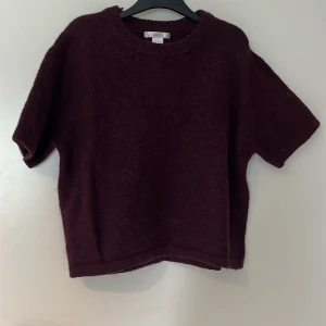 Mörk vinröd stickad tröja kort ärm - Mörkt vinröd stickad tröja med korta ärmar och rund halsringning. Tröjan har en mysig, lite luddig yta och avslappnad passform. Perfekt för lager-på-lager och chill vibes. Passar snyggt tillsammans med ett svart linne 💕