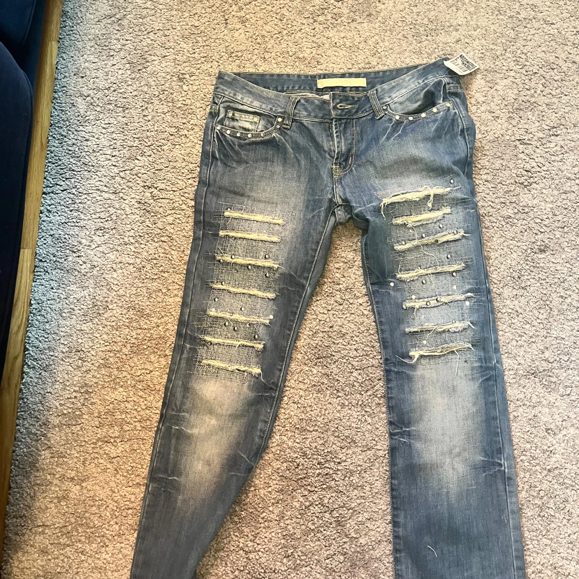 Blå slitna jeans med nitar och detaljer