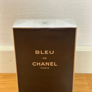 Bleu de Chanel parfym - Bleu de Chanel parfym i elegant mörkblå och silverfärgad kartong med tydlig Chanel-logga på toppen. Klassisk och stilren design från Chanel Paris, perfekt för dig som gillar exklusiva dofter och snygga förpackningar. OANVÄND!