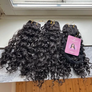 Lockigt löshår 100% äkta hår - Säljer flera buntar mörkbrunt, lockigt löshår från Tianba. Håret är 100% äkta och har täta, definierade lockar. Perfekt för att skapa volym och längd. Fästet är sytt med guldtråd och håret känns mjukt och naturligt.