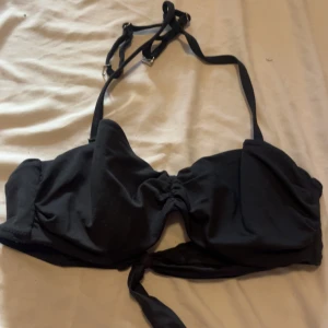 Svart bikiniöverdel från H&M med knyt - Svart bikiniöverdel från H&M i storlek 34. Stilren modell med justerbara axelband och snygg knytning framtill. Perfekt för stranden eller poolen, enkel att matcha med olika underdelar. Gjord i mjukt och bekvämt material.