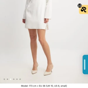 Vit kort klänning med spets från NA-KD - Superfin vit kort klänning från NA-KD med v-ringning och långa ärmar. Klänningen har spetsdetaljer vid byst och slits, samt en mjuk satinliknande yta som ger en lyxig känsla. Perfekt för dig som vill sticka ut med en elegant och stilren look🌺 helt oanvänd!🌸🪻🌞