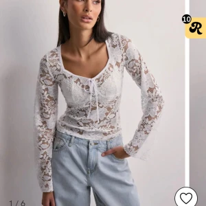 Vit spetsblus från nelly - Superfin vit blus i spets med blommigt mönster och lång ärm. Toppen har v-ringning med söt knytning framtill och är helt i spets. I strlk M, från Nelly. Använd nån enstaka gång. Köpt för 299, säljer för 199. Den finns inte  i lager längre. 