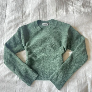 Grön croppad stickad tröja Weekday - Mysig grön stickad tröja från Weekday i croppad modell. Tröjan har rund halsringning, långa ärmar och en lite loose passform. Perfekt att styla med jeans eller kjol för en chill look.