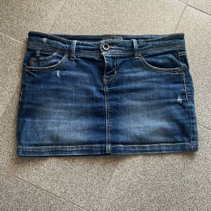 Blå jeanskjol från Cross Jeans - Snygg blå jeanskjol från Cross Jeans med slitna detaljer !!Kjolen har en rak passform och stängs med knapp och dragkedja. Perfekt för dig som gillar en avslappnad och cool stil. Kjolen är lite för liten så den sitter ganska tajt på mig, titta för referens på mina andra uppladdade artiklar💕💕