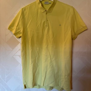 Gul pikétröja från J.Lindeberg - Fräsch gul pikétröja från J.Lindeberg i slim fit-modell. Klassisk krage, korta ärmar och två knappar framtill. Nypris 560kr. Liten defekt på sista bilden, därav priset. 