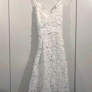 Vit spetsklänning från VILA - Vacker klänning från Vila med v-ringning, stor spets med blommor och korsande axelband bakom ryggen, storlek M. Fint skick hittar inget att anmärka på!   Djur/rökfritt hem