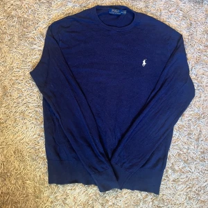 Mörkblå tröja från Polo Ralph Lauren - Klassisk mörkblå tröja från Polo Ralph Lauren med rund halsringning och broderad logga på bröstet. Tröjan är långärmad och har ribbade muddar vid ärmslut och nederkant. Perfekt för en stilren och avslappnad look. Storlek M men mått kan såklart skickas vid osäkerhet. Postas antigen samma dag som köp eller dagen därpå🙌💯