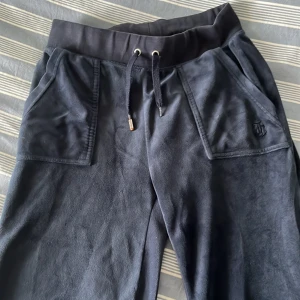 Marinblå juicy coutoure byxor  - Mörkblå fina juicy byxor i fint skick, metallen på ena resorbandet har ramlat av och den andra håller på att rosta lite( se bild) men i övrigt är byxorna i bra skick utan slitage🥰