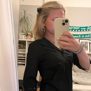 Svart blus med paljett-detaljer - Snygg svart blus med trekvartsärm och paljett-detaljer vid knäppningen och ärmsluten. Skjortan har en klassisk krage och en stilren look som passar perfekt till jeans eller kjol. Materialet känns lätt och bekvämt mot huden.❣️ 