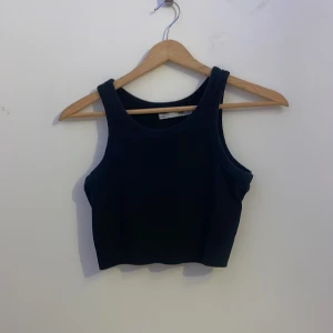 Svart croppad linnetopp från 157 - En svart croppad linnetopp från lager 157 med  rund halsringning och breda axelband. Toppen är enkel och stilren. 