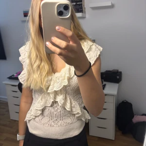 Beige stickad blus med spets från Zara - Supersöt beige stickad blus från Zara med volangdetaljer i spets framtill och på axlarna. Blusen har v-ringning och är ärmlös med breda axelpartier💗💗