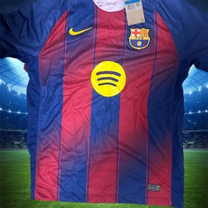 FC Barcelona randig matchtröja Nike - Säljer en officiell FC Barcelona matchtröja från Nike med klassiska blå och röda vertikala ränder. Tröjan har korta ärmar, klubbmärke på bröstet, gul Nike-logga och Spotify som sponsor framtill. Tillverkad i lätt och ventilerande polyester, perfekt för fotboll eller häng.