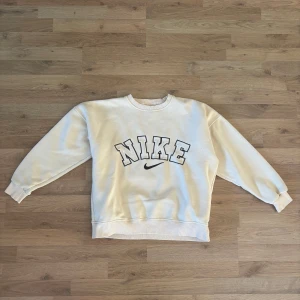 Vintage Nike sweatshirt - Vintage streetwear creamfärgaf tröja / sweatshirt från Nike med stor broderad logga i svart och beige framtill. Perfekt för en chill och sportig look. Materialet är mjuk bomullsmix som känns skönt. Finns några små prickar på två ställen (se bild) men inte varit något problem för mig. 
